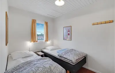 two twin beds in a room with white walls at Agger Havn Feriecenter in Vestervig