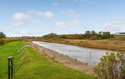 a river with a fence next to a field at Cozy Home In Vestervig With Wifi in Vestervig