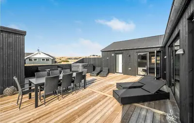 a deck with black chairs and tables on a building at Awesome Home In Harboøre With Kitchen in Harboør