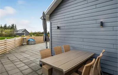 a patio with a wooden table and chairs and an umbrella at 3 Bedroom Beautiful Home In Vemb in Vemb