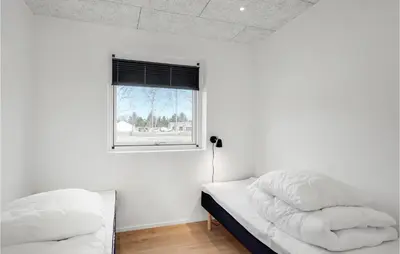 a white bedroom with two beds and a window at Nice Home In Blokhus With Sauna in Blokhus