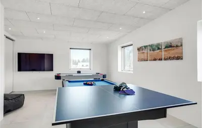 a ping pong table in a room with a tv at Nice Home In Blokhus With Sauna in Blokhus