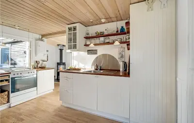 a kitchen with white cabinets and a wooden ceiling at 1 Bedroom Lovely Home In Løgstør in Løgstør