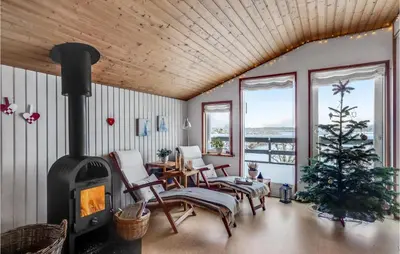 a living room with a fireplace and a christmas tree at 2 Bedroom Awesome Home In Thyholm in Thyholm