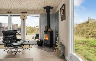 a room with a fireplace and a chair and a window at Stunning Home In Løkken With Kitchen in Løkken