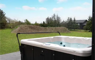 a jacuzzi tub on a patio with a yard at Gorgeous Home In Blokhus With Jacuzzi in Blokhus
