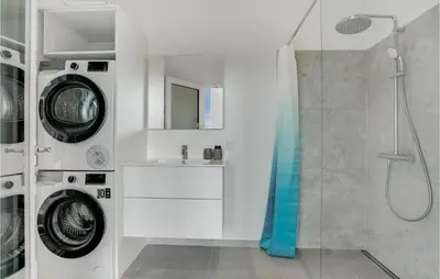 a bathroom with a shower and a washing machine at Gorgeous Home In Blokhus With Jacuzzi in Blokhus