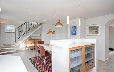 a kitchen and dining room with white walls and a staircase at Holiday Home Egebækvej in Blokhus