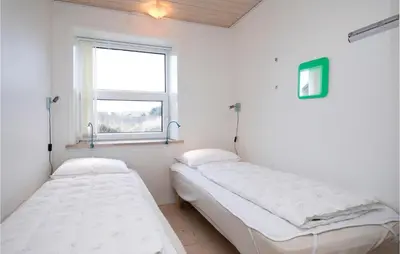 two beds in a room with a window at Holiday Home Egebækvej in Blokhus