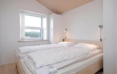 a large bed in a white room with a window at Holiday Home Egebækvej in Blokhus