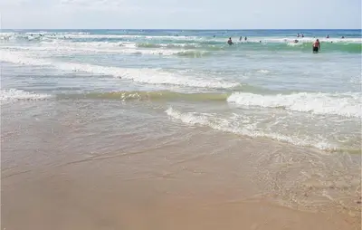 a beach with people swimming in the ocean at Holiday Home Ved Stranden in Blokhus