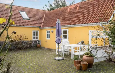 a yellow house with a table and an umbrella at 3 Bedroom Gorgeous Home In Vestervig in Vestervig