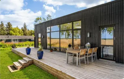 a black house with a wooden deck with a table and chairs at 4 Bedroom Gorgeous Home In Fur in Furland