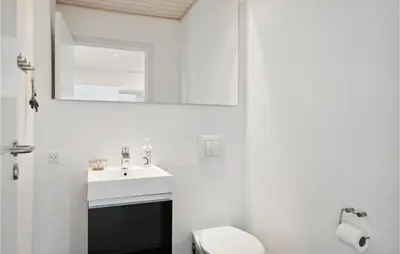 a bathroom with a sink and a toilet and a mirror at Nice Home In Øster Assels With Wifi in Øster Assels