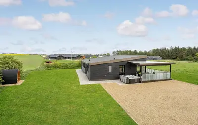 a small house on a field with a grass yard at Nice Home In Spøttrup With Sauna in Spottrup