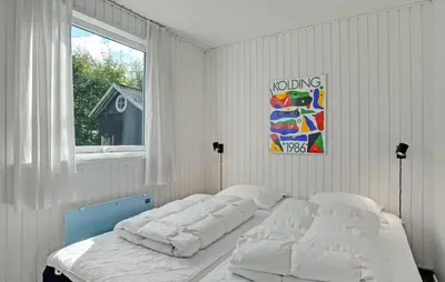 a bedroom with a bed with white sheets and a window at 2 Bedroom Nice Home In Roslev in Roslev