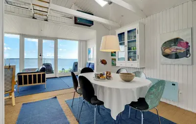 a dining room with a table and chairs and the ocean at 2 Bedroom Nice Home In Roslev in Roslev
