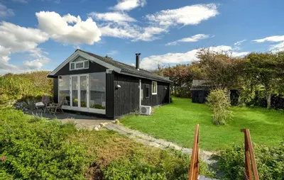 a small black house in a garden with a yard at 2 Bedroom Nice Home In Roslev in Roslev