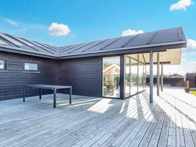 a house with a bench on a wooden deck at Modern Cottage with Spa - By Traum Ferienwohnungen in Vinderup