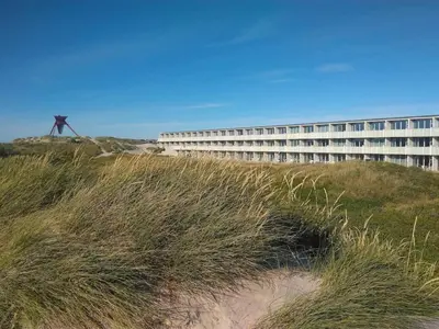 a building on top of a grassy hill next to a building at 6 person holiday home in Blokhus-By Traum in Blokhus