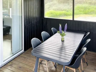 a wooden table with chairs and a vase with purple flowers at 6 person holiday home in Saltum-By Traum in Saltum