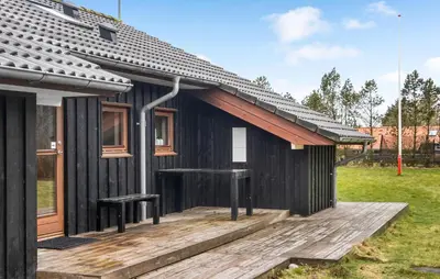 a black house with a wooden deck in a yard at Amazing Home In Spøttrup With Kitchen in Spottrup