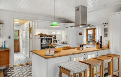 a kitchen with white cabinets and a kitchen island with bar stools at 2 Bedroom Lovely Home In Højslev in Højslev