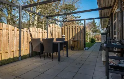 a patio with a wooden fence and a table and chairs at 3 Bedroom Cozy Home In Thyholm in Thyholm