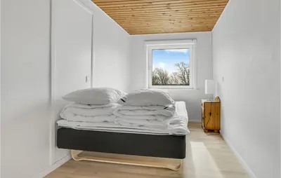 a bedroom with a bed with white walls and a window at 5 Bedroom Stunning Home In Hanstholm in Hanstholm