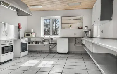 a large kitchen with white appliances and white tile floors at 5 Bedroom Stunning Home In Hanstholm in Hanstholm