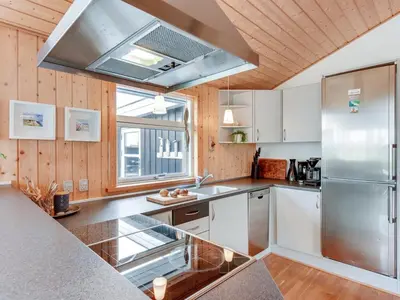 a kitchen with white cabinets and a stainless steel refrigerator at Holiday Home Arni - 150m from the sea by Interhome in Lemvig