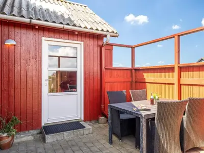 a patio with a table and chairs and a red building at Holiday Home Beatrice - 150m from the sea by Interhome in Lemvig