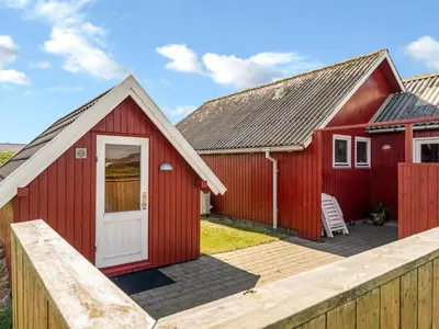 a red house with a white door and a wooden fence at Holiday Home Beatrice - 150m from the sea by Interhome in Lemvig