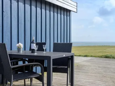 a table and chairs on a deck with a bottle of wine at Holiday Home Rajna - 95m to the fjord by Interhome in Lemvig