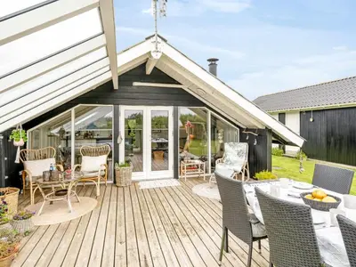 a wooden deck with chairs and a table at Holiday Home Kamile - 400m from the sea by Interhome in Harboør
