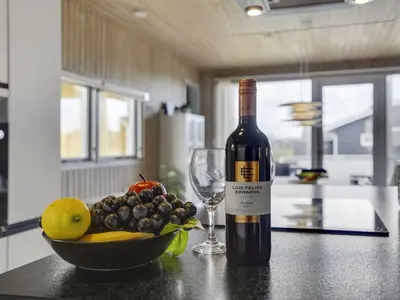 a bottle of wine and a bowl of fruit on a counter at Holiday Home Hebba - 300m from the sea by Interhome in Harboør