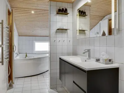 a bathroom with a sink and a tub and a bath tubermott at Holiday Home Hebba - 300m from the sea by Interhome in Harboør