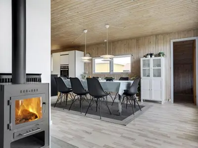 a living room with a fireplace and a dining room at Holiday Home Hebba - 300m from the sea by Interhome in Harboør