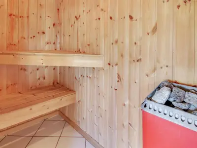 a sauna with a bench and a stove at Holiday Home Suend - from the sea by Interhome in Harboør