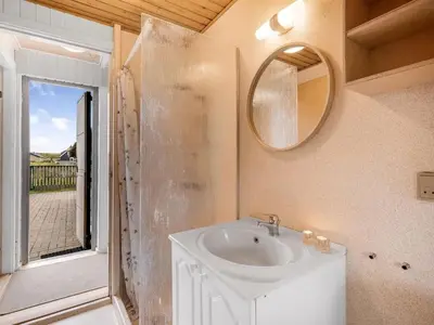 a bathroom with a sink and a mirror at Holiday Home Balthasar - 200m from the sea by Interhome in Harboør