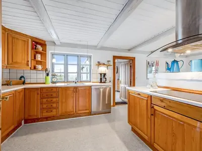 a kitchen with wooden cabinets and stainless steel appliances at Holiday Home Orvo - 150m from the sea by Interhome in Harboør