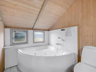 a white bathroom with a tub and a toilet at Holiday Home Mimo - 150m from the sea by Interhome in Harboør