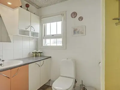 a white bathroom with a toilet and a sink at Holiday Home Hansen - 75m from the sea by Interhome in Harboør