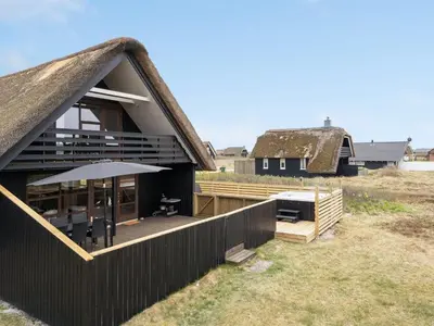 a house with a deck with an umbrella at Holiday Home Kristanna - 150m from the sea by Interhome in Harboør