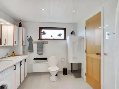 a white bathroom with a toilet and a sink at Holiday Home Kristanna - 150m from the sea by Interhome in Harboør