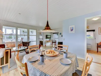 a dining room and living room with a table and chairs at Holiday Home Thamara - 350m from the sea by Interhome in Harboør