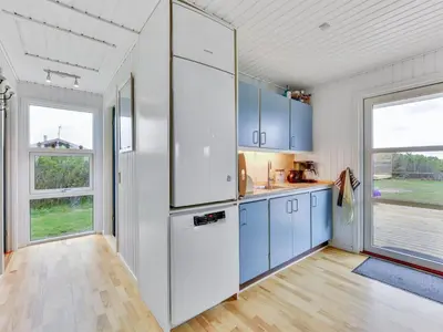 a kitchen with blue cabinets and a white refrigerator at Holiday Home Thamara - 350m from the sea by Interhome in Harboør