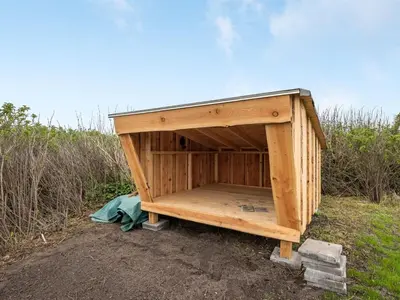 a wooden dog house sitting in a field at Holiday Home Thamara - 350m from the sea by Interhome in Harboør
