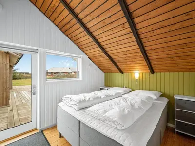 a bed in a room with a wooden ceiling at Holiday Home Olesia - 250m from the sea by Interhome in Harboør