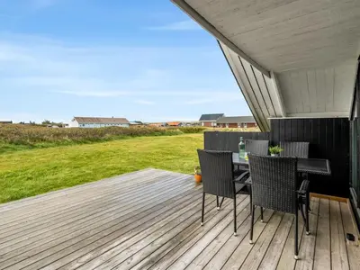 a patio with a table and chairs on a deck at Holiday Home Olesia - 250m from the sea by Interhome in Harboør